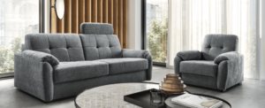 Klasyczna sofa i fotel ze skrzynką z kolekcji Ala marki Sweet sit w ciemnej szarej tapicerce w nowoczesnym salonie.
